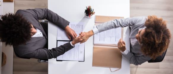 a candidate shakes hands across the table from a hiring manager