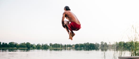 a man jumps into a lake to make a big splash