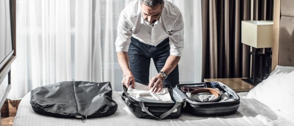 a man packs a suitcase in a hotel bedroom
