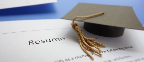 a graduation hat on top of a resume