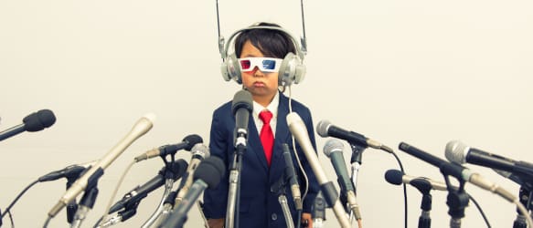 a child in a suit speaks into multiple microphones