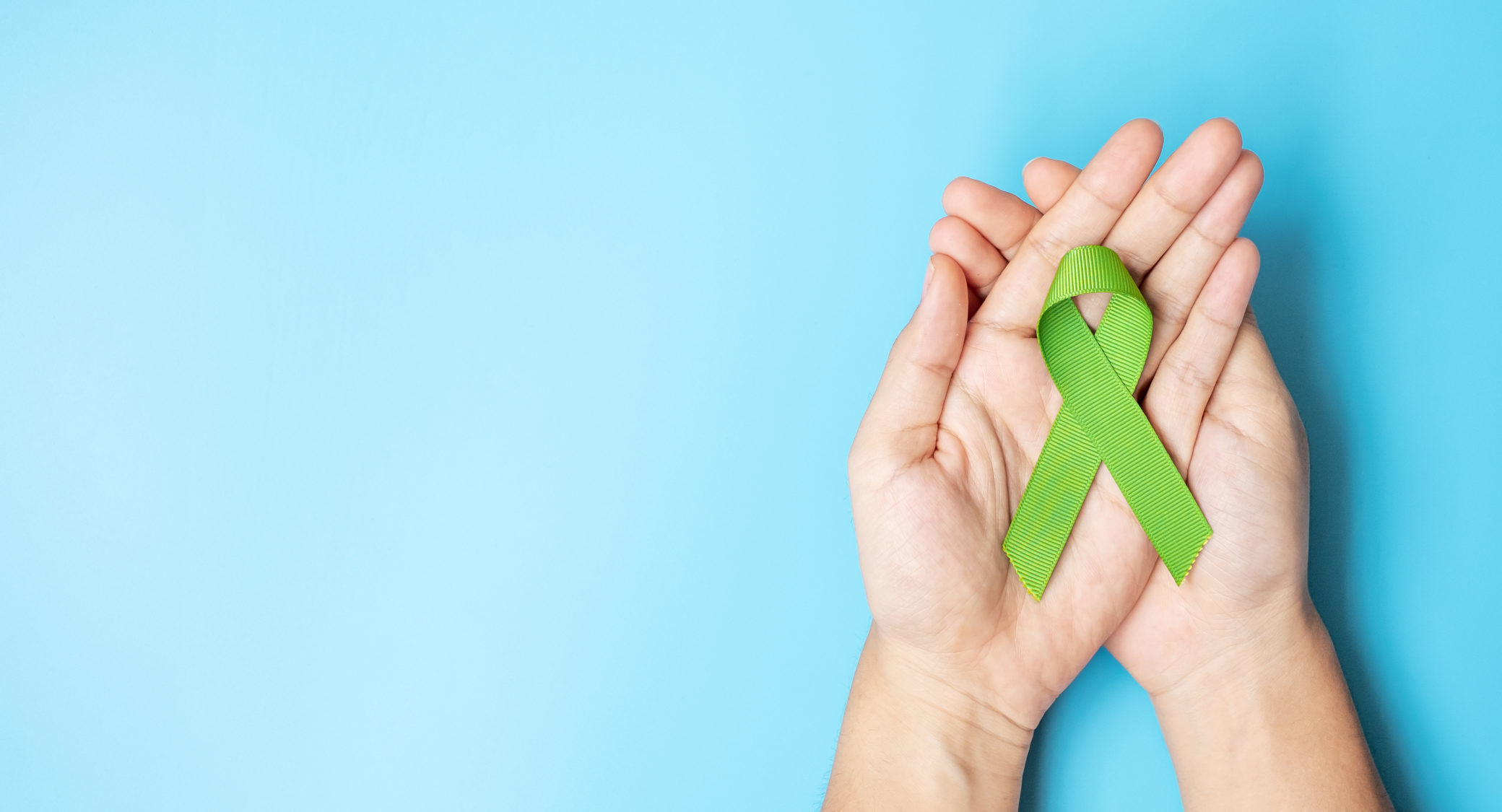 September World lymphoma and October Mental health day Awareness month, Woman holding lime green Ribbon color on blue background for supporting people living, and illness. Healthcare concepts