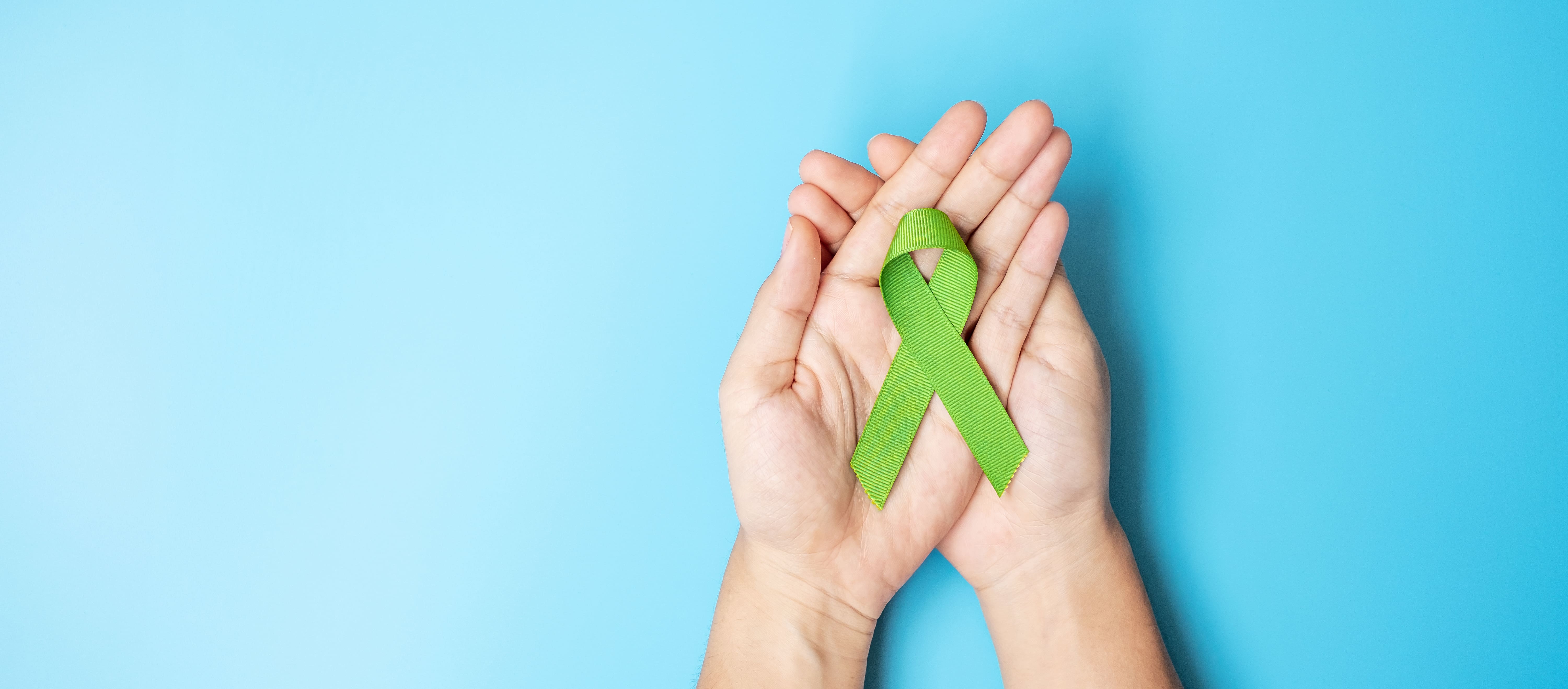 September World lymphoma and October Mental health day Awareness month, Woman holding lime green Ribbon color on blue background for supporting people living, and illness. Healthcare concepts