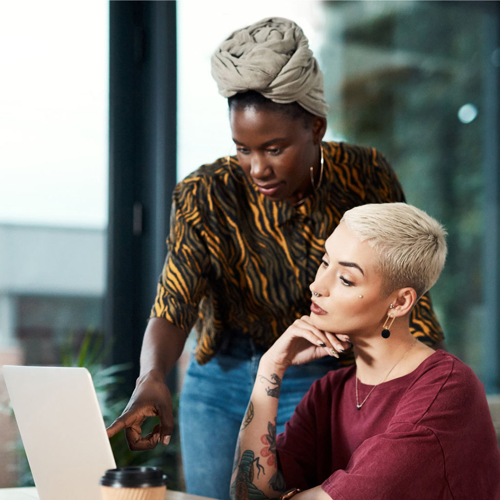 Addison Group's marketing page, two women chatting overlooking an open computer.